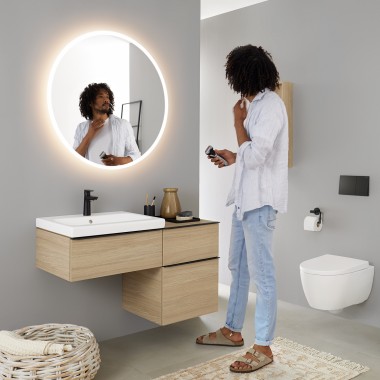 Man looking at himself in a round illuminated Geberit Option mirror Man looking at himself in a round illuminated Geberit Option mirror