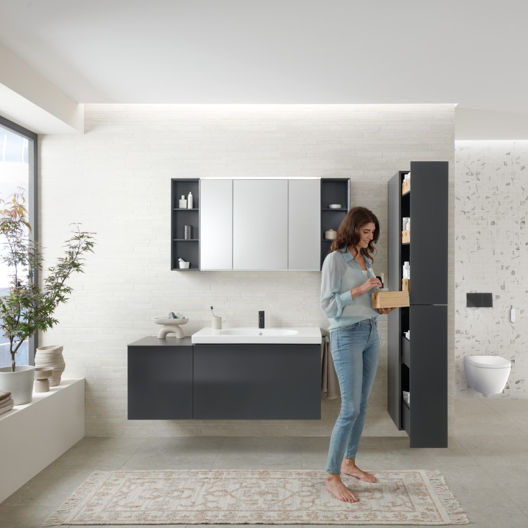 Woman opens tall cabinet with lots of storage space in bathroom with Geberit Acanto bathroom furniture