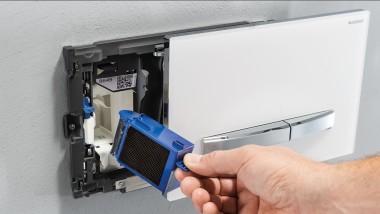 A hand installs the Geberit DuoFresh module in a wall-mounted actuator plate (© Geberit)