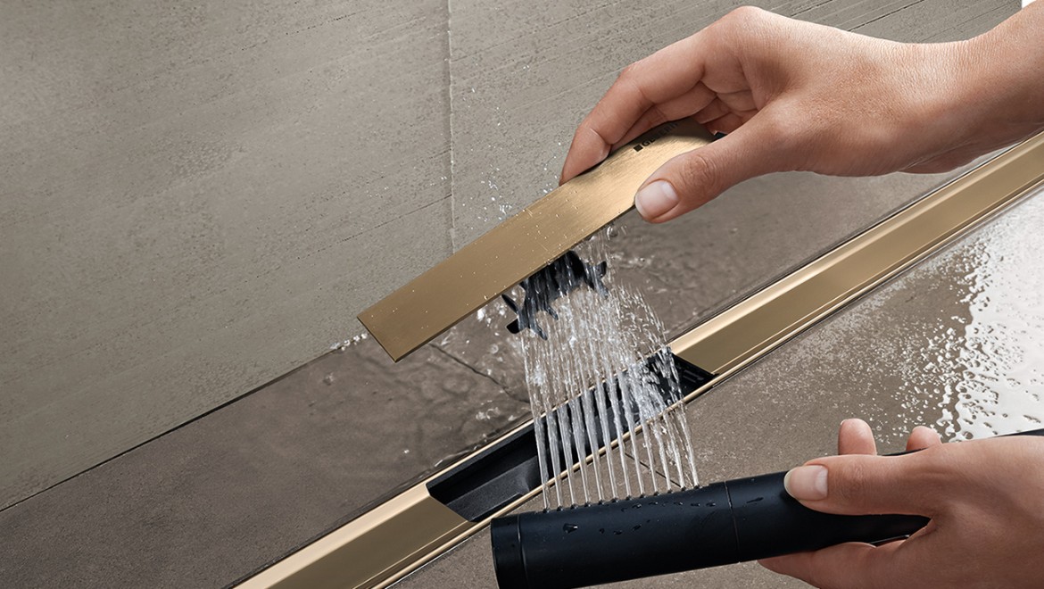 A woman removing the comb insert of the Geberit CleanLine shower channel and cleaning it (© Geberit)