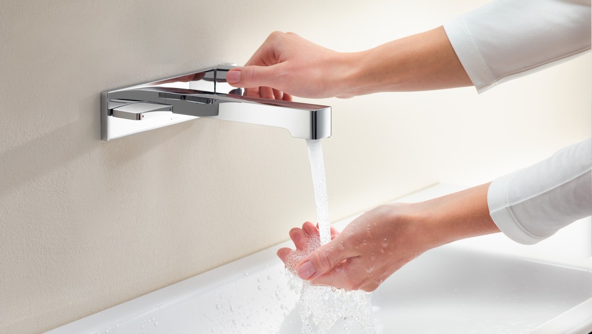 A woman turns on the tap and tests the intensity and temperature of the water jet (© Geberit)