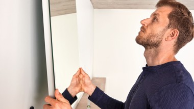 Man hanging up a Geberit Option mirror during a bathroom renovation