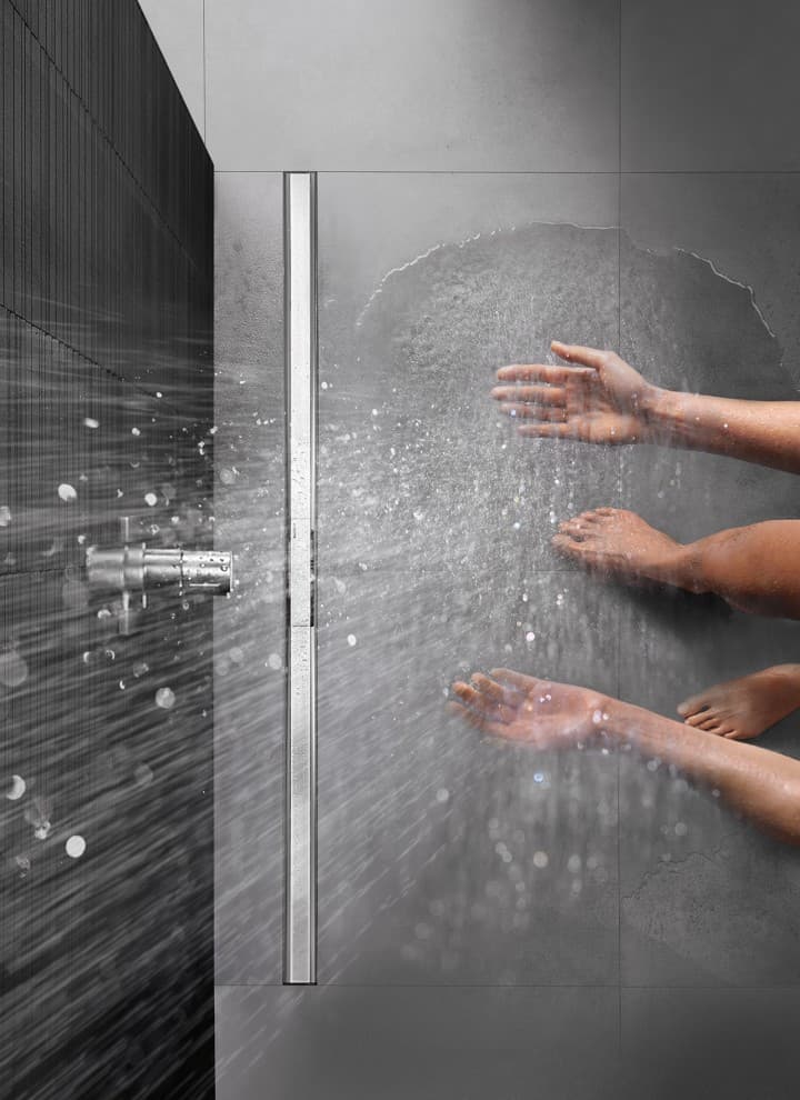 Person showering in a floor-level shower equipped with the Geberit CleanLine shower channel Person showering in a floor-level shower equipped with the Geberit CleanLine shower channel